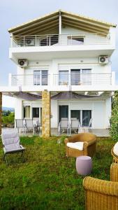uma grande casa branca com cadeiras no quintal em Lovely Sunset -Villa Zoe em Nea Moudania