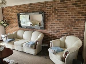 a living room with two white couches and a brick wall at The Junction Estate COOL CALM COZY A Home N Host Property in Wallerawang