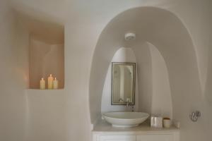a bathroom with a sink and a mirror and candles at Lathouri Cave Villa in Oia