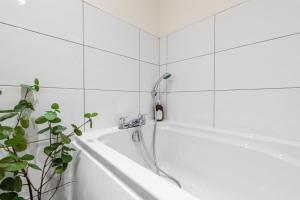 a bathtub with a shower head in a bathroom at Stylish 2 bed apartment close to city in Bradford