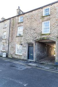an old brick building with a blue door on a street at Cosy, Boutique Central Kirkby Lonsdale Apartment in Kirkby Lonsdale