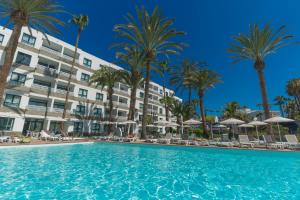 a swimming pool in front of a hotel with palm trees at Alsol Walhalla in Playa del Ingles
