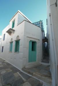 a white building with green doors on the side at Παραδοσιακό Σπίτι στον Πύργο in Panormos