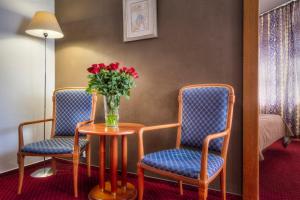 a room with two chairs and a table with a vase of flowers at Hotel Harmony in Prague