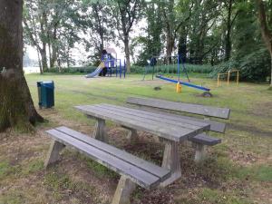 a wooden bench in a park with a playground at Pipowagen Bergeijk in Bergeijk