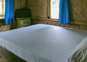 Cama grande en habitación con cortinas azules en Lembah Cawene Hills Syariah RedPartner en Gunungpicung