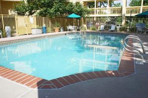 ein großer Pool mit Stühlen und Sonnenschirmen in der Unterkunft La Quinta Inn by Wyndham Denver Northglenn in Westminster