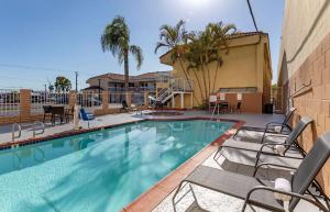 a swimming pool with chairs and a building at Quality Inn Long Beach - Signal Hill in Long Beach