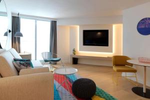 a living room with a couch and a tv at QT Bondi in Sydney