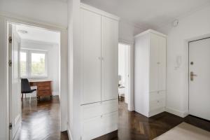 Apartament Muranów في وارسو: غرفة بيضاء مع دواليب بيضاء ومكتب