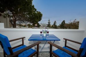 un tavolo blu con due sedie e due bicchieri di vino di Maraki's Little House Santorini a Kamari