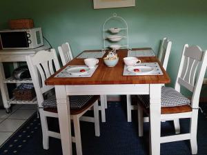 einen Tisch mit weißen Stühlen und einen Holztisch mit Geschirr darauf in der Unterkunft Gästehaus Melz Schwabe in Scharbeutz