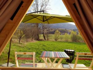 einen Picknicktisch mit einem grünen Regenschirm und zwei Stühlen in der Unterkunft Lika Sunset in Ličko Lešće