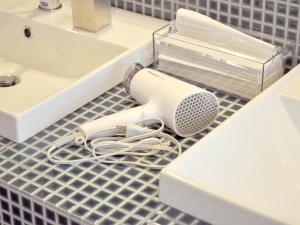 a hair dryer on a bathroom counter next to a sink at Guest House Takazuri-KITA in Nanto