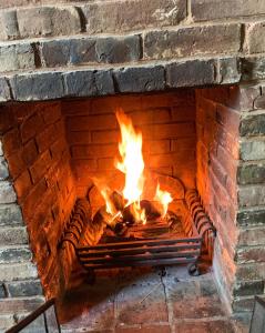 a brick fireplace with a fire in it at Stoop Cottage - in the heart of Quorn in Quorndon