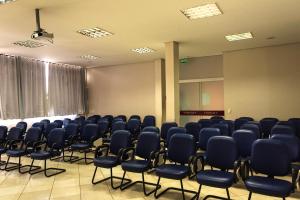 an empty room with blue chairs in it at Treville Hotel in Caràzinho