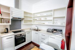 una cocina blanca con armarios blancos y fregadero en Eden Studios, en Mahe