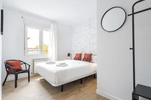 a white bedroom with a bed and a chair at Vallecano Apartments by Olala Homes in Madrid