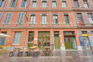 a building with tables and chairs in front of it at LE CODRUS - Charmant appartement dans l'hyper centre toulousain in Toulouse