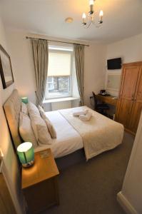 a bedroom with a bed and a desk and a window at All Seasons Guest House in Windermere