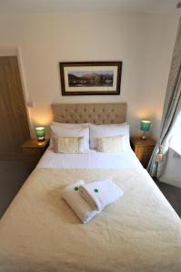 a bedroom with a white bed with two towels on it at All Seasons Guest House in Windermere