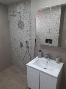 a bathroom with a sink and a shower with a mirror at Sandanski city center apartment in Sandanski