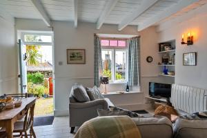 
a living room filled with furniture and a window at Cosy Mousehole Cottage With Sea Views in Mousehole
