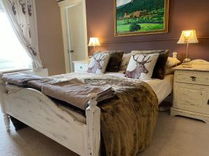 a bedroom with a white bed and a painting on the wall at Thropton Demesne Farmhouse B&B in Rothbury