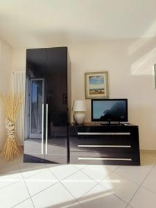 een woonkamer met een tv en een zwart entertainmentcentrum bij Palace Britannique Love and magic in Bordighera in Bordighera