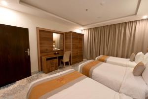 a hotel room with two beds and a desk at Azard Hotel in Al Madinah