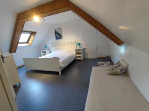 a attic bedroom with a bed and a couch at Petite et grande longères familiale avec jardin - nature & plages in Limerzel