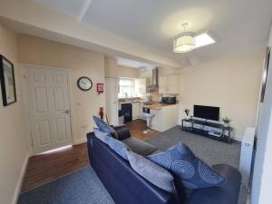 a living room with a blue couch and a kitchen at Perfect Location 2 BR serviced apartment Nr Bike Park Wales & Brecon Beacons in Merthyr Tydfil
