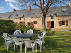 einen Tisch und Stühle vor einem Steinhaus in der Unterkunft Petite et grande longères familiale avec jardin - nature & plages in Limerzel