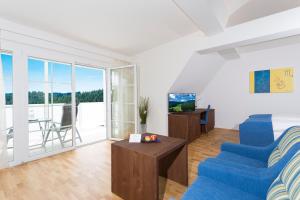 sala de estar con sillas azules y TV en Joglland Hotel Prettenhofer en Wenigzell