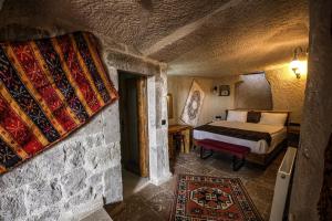 1 dormitorio con 1 cama en una habitación de piedra en Avilla Cave Hotel, en Göreme