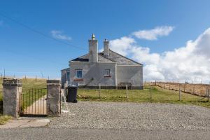 une vieille maison dans un champ avec une clôture dans l'établissement 27 Garenin, à Carloway