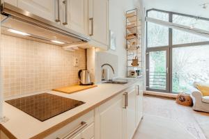 a kitchen with white cabinets and a large window at Boutique apartments - Central Old Town in Banská Štiavnica