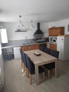 eine Küche mit einem Holztisch und Stühlen sowie eine Küche mit einem Kühlschrank in der Unterkunft Bel Appartement lumineux avec extérieur in Rosières-aux-Salines