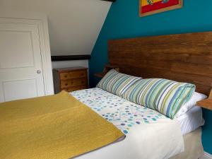 Schlafzimmer mit einem Bett mit einem Kopfteil aus Holz und einem Kissen in der Unterkunft Wynards Farm in Winfrith Newburgh