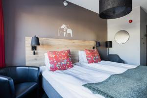 um quarto com uma cama com almofadas vermelhas e uma cadeira em Hotell Fridhemsgatan em Mora