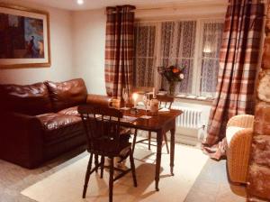 a living room with a table and a leather couch at Virginia Cottage in Bulwick