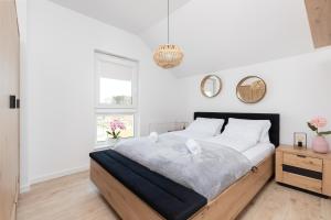 a white bedroom with a large bed and a window at Południowa Przystań Dębki by Renters in Dębki