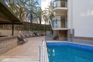 a swimming pool next to a building with palm trees at Yuvam Prime Beach Hotel in Marmaris