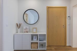 un miroir sur une étagère blanche à côté d'une porte dans l'établissement Paim XXI Azores Apartment, à Ponta Delgada