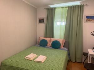 リスボンにあるハウス アンド ルームズ イン リスボンのベッドルーム1室(緑のベッド1台、タオル2枚付)