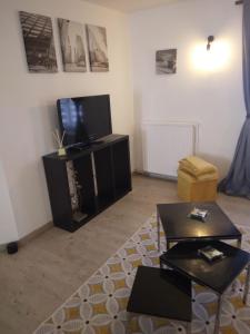 ein Wohnzimmer mit einem Flachbild-TV und Tischen in der Unterkunft Bel Appartement lumineux avec extérieur in Rosières-aux-Salines