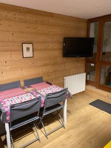 a dining room with a table and chairs and a flat screen tv at Studio Confortable style Chalet, Saint Lary Soulan centre village, 6 nuits minimum in Saint-Lary-Soulan