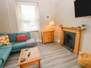 a living room with a green couch and a fireplace at 54 Pencoed Road in Burry Port