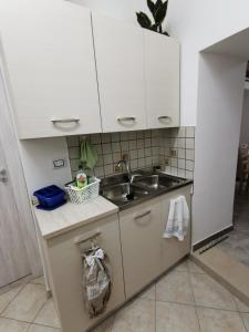 eine kleine Küche mit weißen Schränken und einem Waschbecken in der Unterkunft House Umberto I in Viagrande