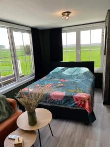 a bedroom with a bed and a table and windows at Tiny House in Westdorpe